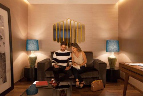 a man and woman sitting on a couch in a living room at BessaHotel Liberdade in Lisbon