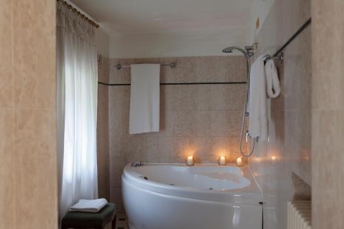 La salle de bains est pourvue d'une baignoire blanche et de bougies. dans l'établissement Hotel Villa Giona, à San Pietro in Cariano