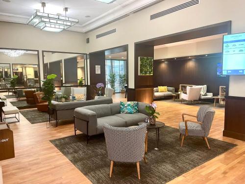 a lobby with a couch and chairs and a television at Mercure Paris Velizy in Vélizy-Villacoublay