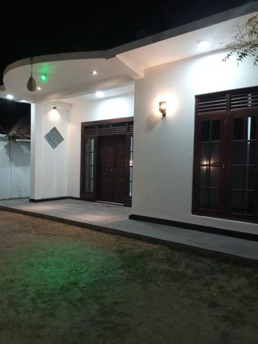 a white house with brown doors and a yard at NOVA Guest in Mirissa