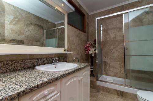 a bathroom with a sink and a glass shower at Ocean View Apartment - Pool and Sea View & Albufeira Center in Albufeira