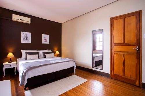 a bedroom with a large bed and a wooden door at Hotel Gambrinus in Poços de Caldas
