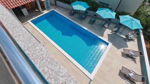 an overhead view of a swimming pool with chairs and umbrellas at Apartmani "Villa Barbara" in Novalja