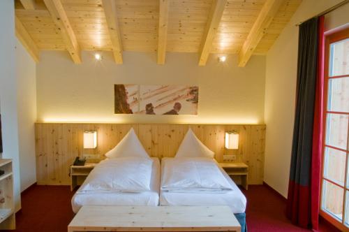 a room with two beds and two tables at Der Waldhof in Sankt Anton am Arlberg