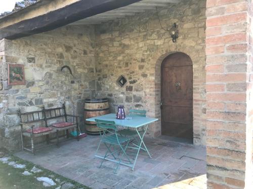 a patio with a table and a bench and a wooden door at Il Fiorino di Badia in Badia A Passignano
