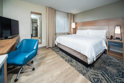a hotel room with a bed and a desk and a blue chair at Candlewood Suites Charleston – Mt. Pleasant by IHG in Charleston
