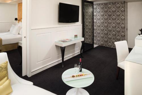 a room with a bed and a table and a tv at Hotel Colón Gran Meliá - The Leading Hotels of the World in Seville