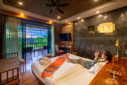 a woman laying on a bed in a bedroom at Andalay Beach Resort Koh Libong in Ko Libong