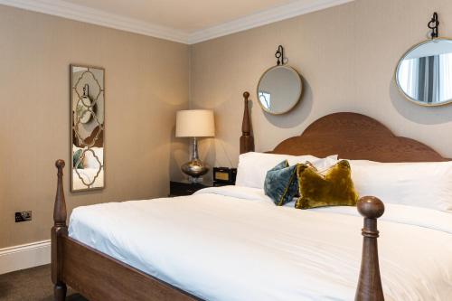 a bedroom with a large bed with two mirrors on the wall at King Street Townhouse in Manchester