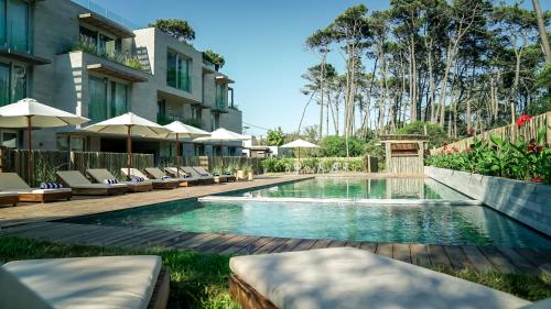 a swimming pool with chairs and umbrellas next to a building at Casagrande Hotel & Beach Club in José Ignacio