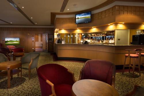 a restaurant with a bar with chairs and tables at The Oxfordshire Golf & Spa Hotel in Thame