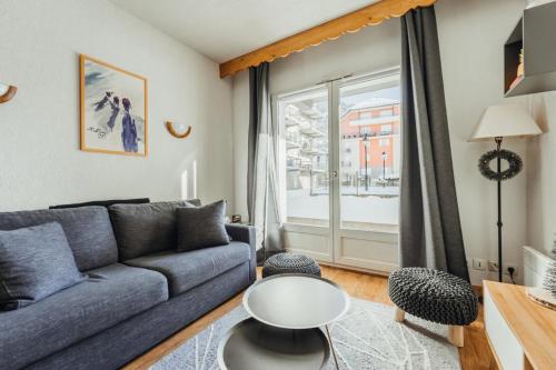 ein Wohnzimmer mit einem Sofa und einem Fenster in der Unterkunft Apartment with a furnished terrace close to the cable cars Rated 3 stars in Saint-Gervais-les-Bains