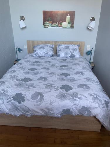 a bed with a blue bedspread with flowers on it at résidence des bains in Veules-les-Roses