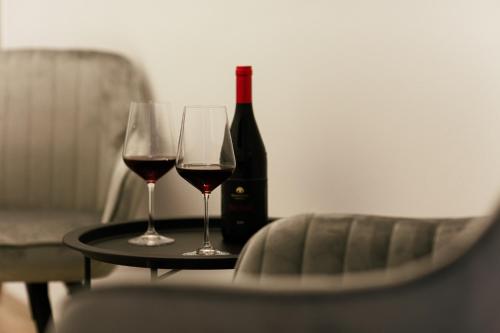 two glasses of wine on a table with a bottle of wine at Munkácsy Villa - Szekszárd in Szekszárd