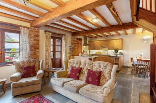 a living room with a couch and chairs and a kitchen at Shire Cottage in Broadway