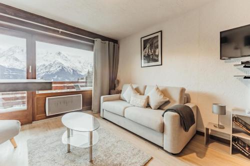 een woonkamer met een bank en een groot raam bij Furnished studio on the ski slopes with a terrace & panoramic views in Saint-Gervais-les-Bains