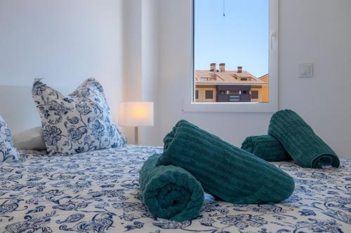 a bed with green pillows on it with a window at L'Ancora Beach in Jávea