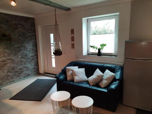 sala de estar con sofá de cuero negro y 2 mesas en Holiday Nr,3, en Immenstedt