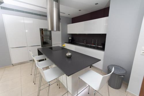 a kitchen with a black table and white chairs at Spacious Fully Equipped 3BD 2Bath Apt in the heart of city with Balconies AC and fast WIFI #2 in Heraklio Town