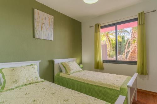 1 dormitorio con 2 camas y ventana en Villa Rosa with private pool by HR Madeira, en Ribeira Brava