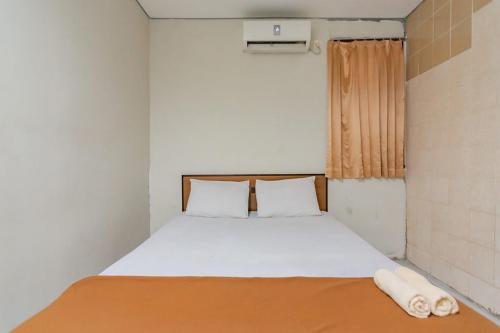een bed in een kleine kamer met een raam bij Mahkota Intan Syariah Balikpapan RedPartner in Balikpapan