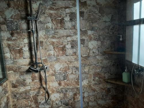 a bathroom with a shower with a stone wall at Casa Rural El Arroyo in Sotoserrano