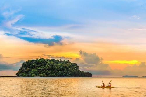 two people in a boat in the water with an island at Andalay Beach Resort Koh Libong in Ko Libong
