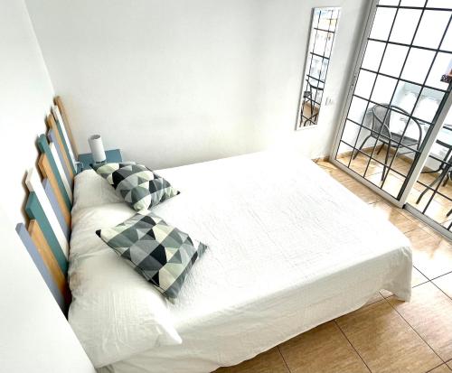 Schlafzimmer mit einem Bett mit weißer Bettwäsche und Kissen in der Unterkunft Sea Soul Apartment Puerto Santiago in Puerto de Santiago