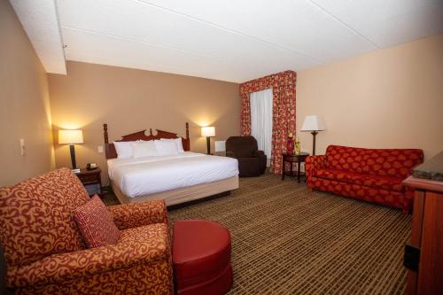 a hotel room with a bed and a couch and a chair at Baymont by Wyndham Knoxville/Cedar Bluff in Knoxville