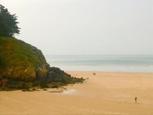 a beach with people walking on the sand at Grand studio Clémenceau Vue mer 3 étoiles in Pléneuf-Val-André