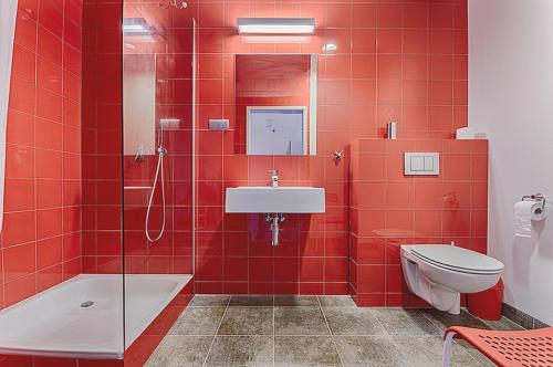 a red tiled bathroom with a toilet and a sink at Apartamenty Poli House in Krynica Morska