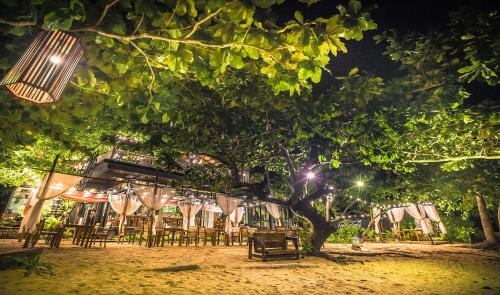a group of tables and chairs under a tree at night at Andalay Beach Resort Koh Libong in Ko Libong