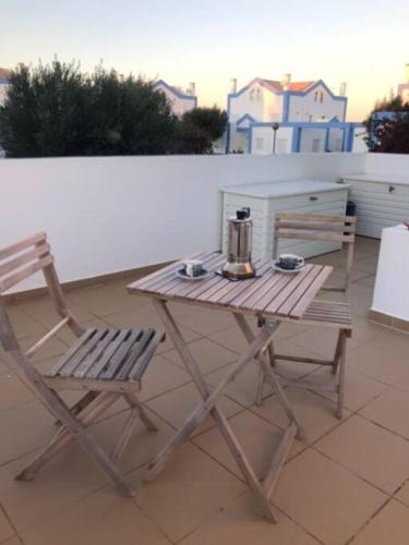 a wooden table and a chair on a patio at CASA NA COLINA - MORADIA com PISCINA in Tavira