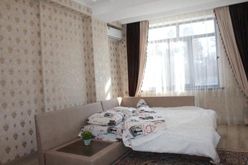 a bedroom with a bed with pillows and a window at Отдельная квартира с видом на Ботанический садWiFi in Bishkek