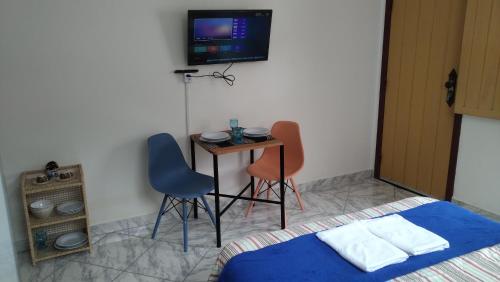 a bedroom with a table and two chairs and a tv at Trenzin de Aconchego Apto no Centro Histórico in Ouro Preto