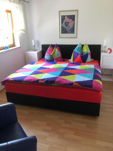 ein Schlafzimmer mit einem Bett mit einer bunten Bettdecke und Kissen in der Unterkunft Ferienwohnung am Rohrbacherhof Sabine Rück in Barackenhöfe