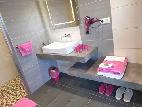 y baño con lavabo, toallas rosas y zapatos rosados. en La Bulle Des Anges, en Illoud