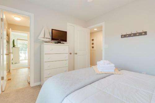 a white bedroom with a bed and a tv at Sounds Great! in Duck