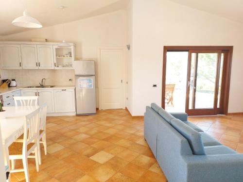 a living room with a blue couch and a kitchen at Villa Gallura Dream with private pool and sea view in Tanaunella