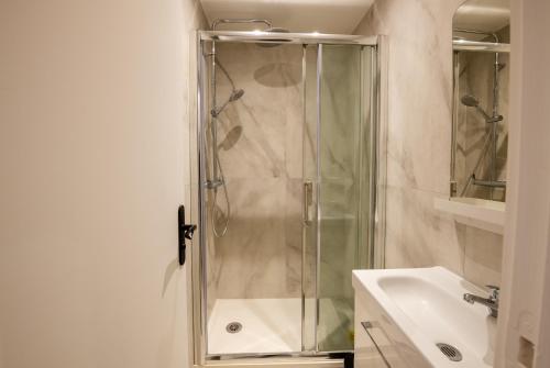 une douche avec une porte vitrée dans une salle de bain dans l'établissement APPARTEMENT CONTEMPORAIN RÉPUBLIQUE - TEMPLE 2, à Paris