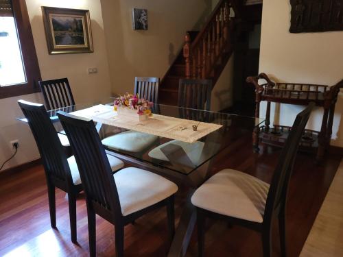 a dining room with a glass table and chairs at El Cameliar - Vibañu in Vibaño