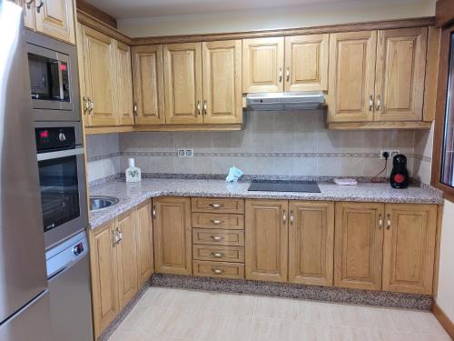 a kitchen with wooden cabinets and stainless steel appliances at El Cameliar - Vibañu in Vibaño