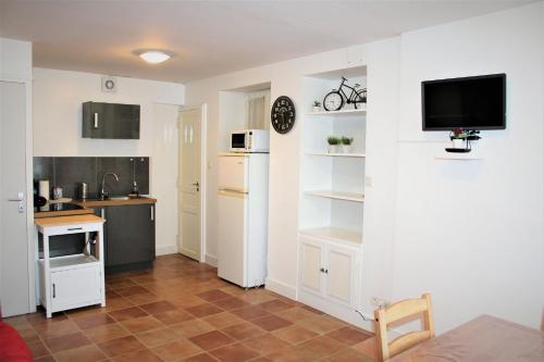 Il comprend une cuisine avec des placards blancs et une télévision murale. dans l'établissement Gîte de Ponpon, à proximité du Zoo et des Châteaux de la Loire, à Selles-sur-Cher