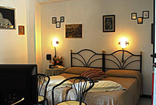 a bedroom with a bed with two chairs and two lights at Hotel Ebe in San Piero a Sieve