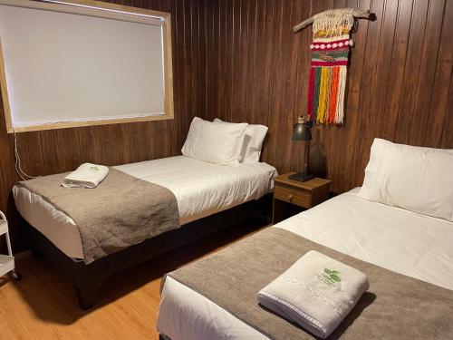 a small room with two beds and a window at Cabañas Las Lengas in Puerto Natales