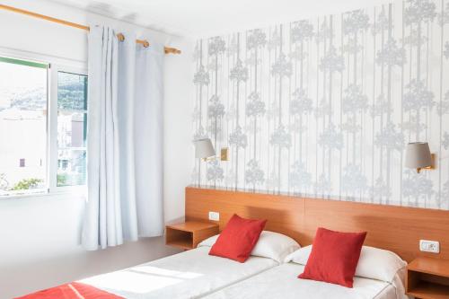 ein Schlafzimmer mit einem Bett mit zwei roten Kissen in der Unterkunft Hotel Apartamentos Villa Gomera in San Sebastián de la Gomera