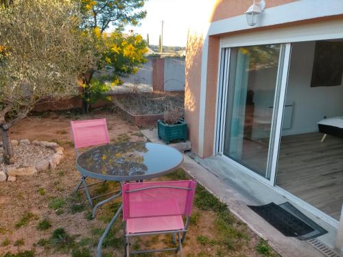 un patio con mesa y 2 sillas rosas en Chez Michele et Jean Louis, en Pignans