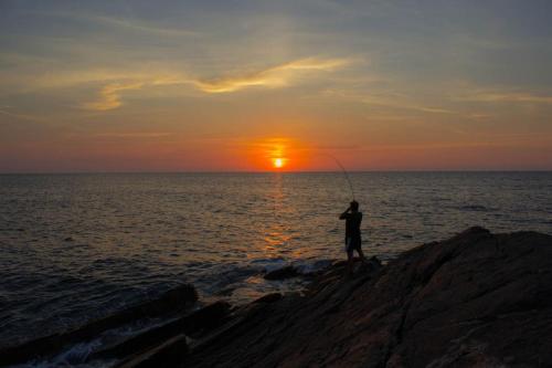 a man fishing on the rocks at the ocean at Calascoglietti in Stintino