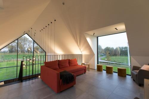 a living room with a red couch and large windows at Vakantiewoning Trimaarzate in Zwevegem