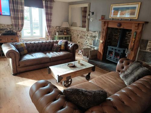 a living room with leather couches and a fireplace at Le Breil Furet in Ménéac